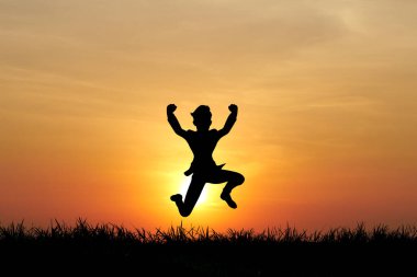 Büyüleyici bir günbatımı arkaplanına karşı sevinçle sıçrayan bir insanın silueti özgürlük ve mutluluğun özünü yakalıyor..