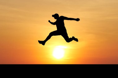 Canlı bir gün batımının önüne atlayan bir insanın silueti özgürlük ve macerayı simgeliyor..