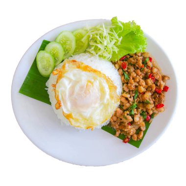 A vibrant dish featuring Thai basil chicken, rice, and a fried egg, garnished with fresh cucumber, lettuce, and cabbage.