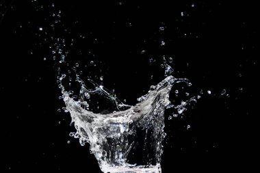 Suyun yüksek hızda yakalanması siyah bir zemine çarpıyor, çarpıcı bir hareket ve enerji sergiliyor..