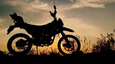 Canlı bir günbatımı gökyüzüne karşı dizilmiş macera motosikleti silueti özgürlük ve keşfin özünü yakalıyor..