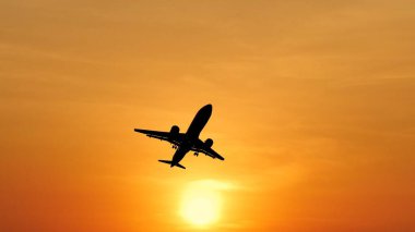Çarpıcı turuncu bir gün batımında uçan uçak silueti seyahat ve maceranın özünü yakalıyor..
