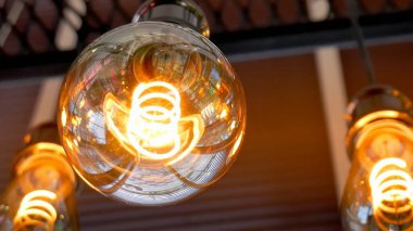 Modern ya da endüstriyel temalı projeler için mükemmel olan karmaşık iplik dizaynını gösteren parıldayan bir Edison ampulünün detaylı bir görüntüsü.