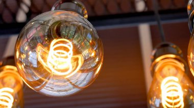 Parlayan klasik Edison ampullerinin detaylı bir görüntüsü modern endüstriyel ortamda karmaşık lifler sergiliyor..