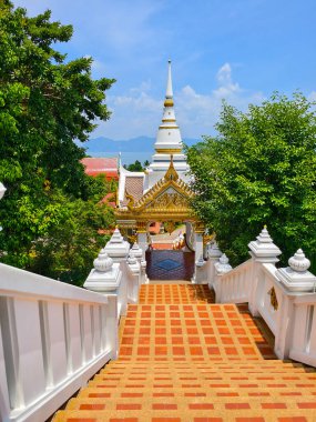 Bereketli yeşillik ve canlı gökyüzü ile çevrili karmaşık mimari içeren güzel Tayland tapınağı..