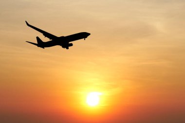 Uçak silueti rengarenk bir günbatımı gökyüzünde süzülüyor, seyahat ve maceranın özünü yakalıyor..