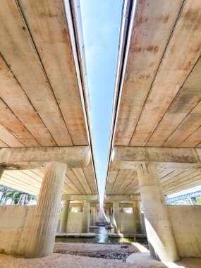 Modern beton bir köprünün alçak açılı çekimi simetriyi ve mimari tasarımı berrak mavi gökyüzüne karşı sergiliyor..