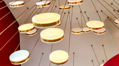 Çağdaş bir alanda dairesel tasarımlar ve sıcak ışıklandırma içeren modern bir tavan lambasının yakın çekimi.