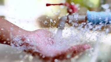 Ferahlatıcı su musluktan ellere sıçrıyor, su ve temizliğin özünü yakalıyor..