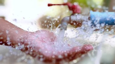 Ferahlatıcı su musluktan ellere sıçrıyor, doğal ortamda bir temizlik ve su akışını yakalıyor..