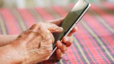 Yaşlıların ellerinin akıllı bir telefonla etkileşime girerek, yaşlılar arasında teknoloji kullanımını vurguluyor.