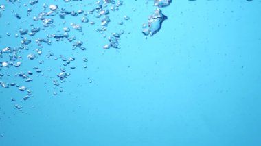 Açık mavi bir zemin üzerinde kabarcıklar yükselen yakın plan, ferahlatıcı ve sakin bir su altı anı yakalamak.
