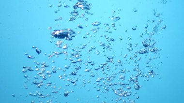 Açık mavi arkaplana karşı temiz suda yükselen kabarcıkların yakın plan görüntüsü ferahlatıcı ve dinamik bir su altı anını yakalıyor..