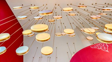 Kırmızı ve beyaz aksanlı modern bir iç mekanda dairesel kolye ışıkları olan bir tavanın soyut görüntüsü.