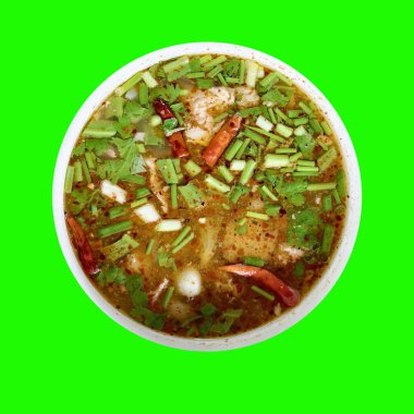Taze otlar ve kırmızı biberlerle süslenmiş baharatlı Tayland Tom Yum çorbası. Parlak yeşil arka planda izole edilmiş..