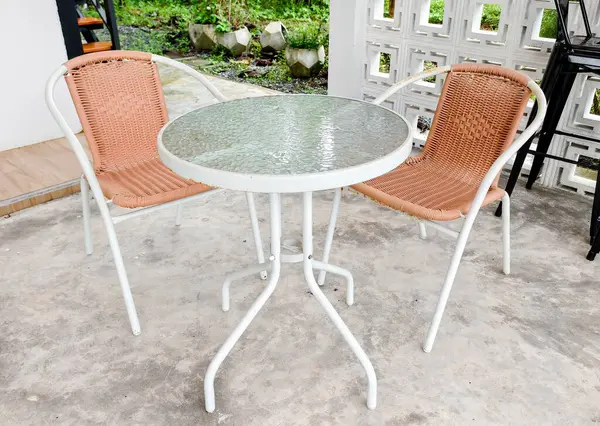 İçinde cam bir masa ve iki dokuma sandalye olan rahat bir bahçe seti. Bahçe ortamında dinlenmek için mükemmel..