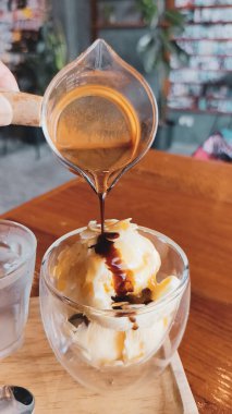 Vanilyalı dondurmanın üzerine dökülen espresso 'nun yakın çekimi, rahat bir kafe ortamında lezzetli bir affogato yaratıyor..