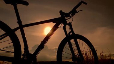 Günbatımı arka planında bir bisikletin silueti