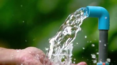 Bahçede fıskiyeyi tutan bir elin yakın çekimi.