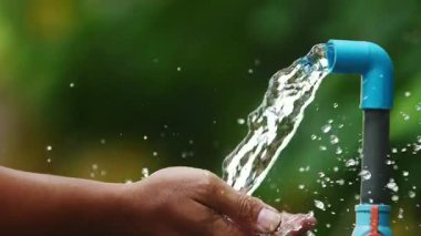 Adam hortumla bahçeyi suluyor.