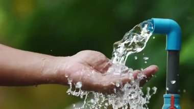 Parkta ellerini fıskiyeyle yıkayan bir kadın.