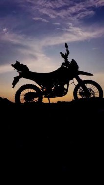 Gün batımının arka planında motosiklet silueti