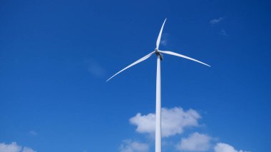 Ön planda mavi gökyüzü ve bulutlu yel değirmeni santrali.