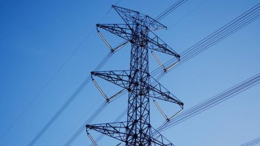 Mavi gökyüzü arka planında yüksek voltaj pilonu.