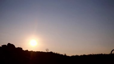 Gün batımının arka planında sırt çantalı bir adamın silueti.