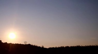 Alacakaranlıkta dağın tepesinde bir adamın silüeti.