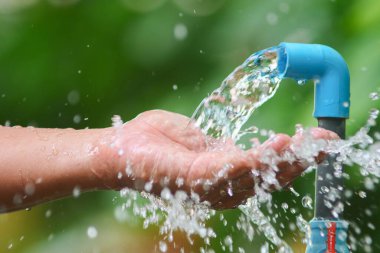 Mavi borudan ellere akan suyun yakın çekimi tazeliği ve sürdürülebilirliği sembolize ediyor..