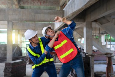 Kıdemli kadrolu mühendis, genç bir adama küçük bir kütüğün düşmesine yardım ediyor. İnşaat alanında çalışan mühendisler, güvenlik, risk yönetimi, iş yerinde risk yönetimi. 