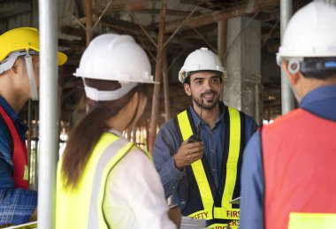 engineer project manager holding walkie talkie talking to work team on the building under construction,engineer teams wearing full safety gear while work on height complex and dangerous construction sites