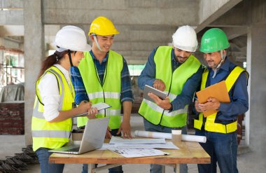 engineering teams meeting and discussing under construction building, engineer project manager smile, explain works with tablet to senior foreman