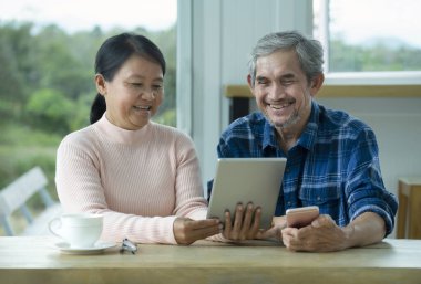 romantic senior married couple sharing computer tablet and chatting online with their children together.concept elderly lifestyle, technology, modern long distance communication,family relationship