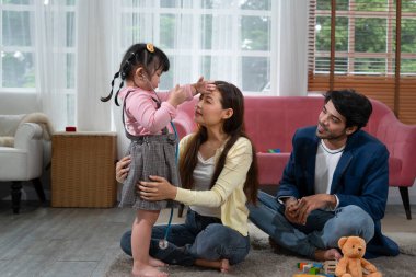 mother and father spend time with little kid in the living room, daughter playing with stethoscope to examine her mother, concept family relationship,lifestyle