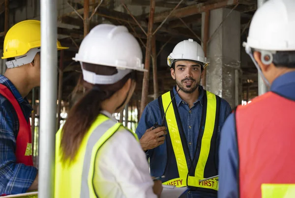 engineer project manager holding walkie talkie talking to work team on the building under construction,engineer teams wearing full safety gear while work on height complex and dangerous construction sites