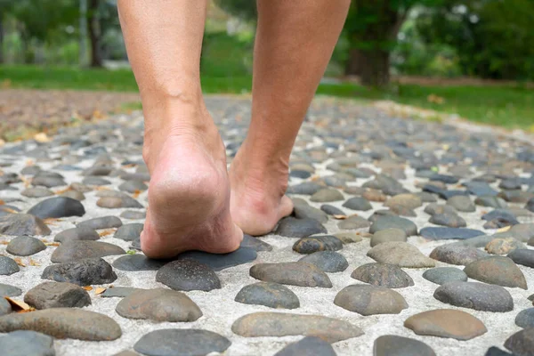 barefoot old man stepping on stones,foot reflexology at the park.concept of foot massage for increase blood circulation in elderly,relief for tired and sore feet