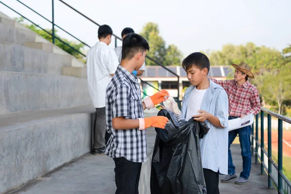 group of private sector volunteer teens and teacher help collect garbage in the stadium after the sporting event, concept teens volunteering, engage young people to help society