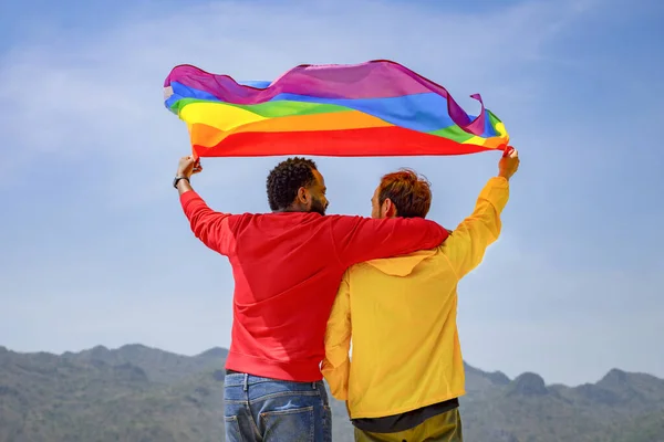 五彩缤纷的同性恋夫妇身穿五彩缤纷的衣服 肩并肩地站在一起 举着摇曳着的Lgbt旗 代表着自由的空气 支持着Lgbt社区平等运动 — 图库照片