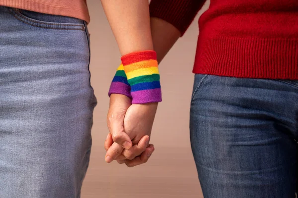 stock image romantic lesbian lover wear lgbt rainbow wristband hands holding support each others, concept of lgbtq community equality movement, lgbtq happy pride month