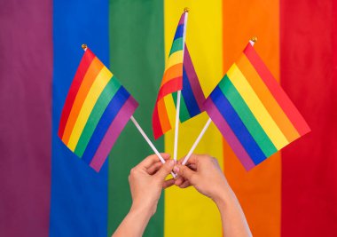 renkli lgbt gökkuşağı bayrak çizgileri arka plan ve ellerde gökkuşağı bayrakları, lgbtq topluluk kutlaması ve hareketi konsepti, lgbtq mutlu gurur ayı  