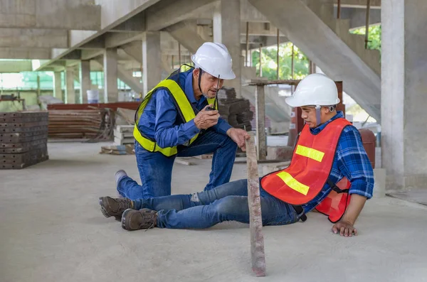 accident in site work,iron piece fell from height hit on a worker\'s legs at site, a colleague rescued him from  accident and walkie-talkie call first aid team.concept risk management, safety at work