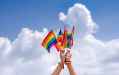 İnsanlar ellerinde lgbt rengarenk gökkuşağı arka plan mavi gökyüzü, lgbtq çeşitliliği kavramı sevgi, aktivist, haklar, protesto, hareket geçidi, kutlama, festival, lgbtq + mutlu gurur ayı