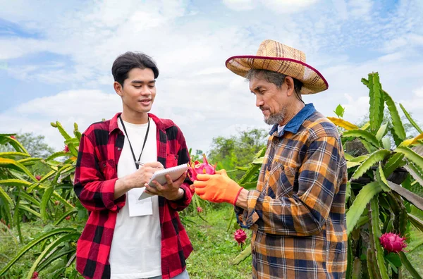young man researcher interview senior man farmer for collect data and take note on notebook at dragon fruit farm,concept agricultural research,dragon fruits planting,development,dragon fruit research