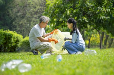 Dedem torunu plastik çöpleri toplaması için destekliyor. Parktaki plastik şişeleri ayırıyor. Gönüllülük bilincini artırıyor.