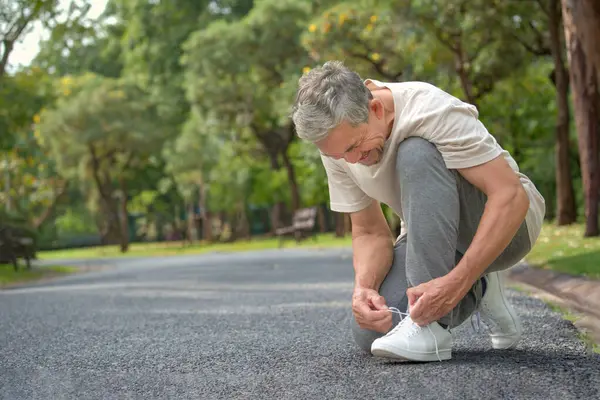 senior man tying shoelace getting ready for exercise, concept of preventing the risk of falls in the elderly