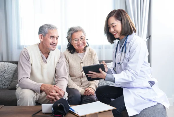 young kind asian female doctor in uniform visiting a senior patient at home,evaluate,collect data and provide advice patient care on tablet,concept of aging care,home care,home health care
