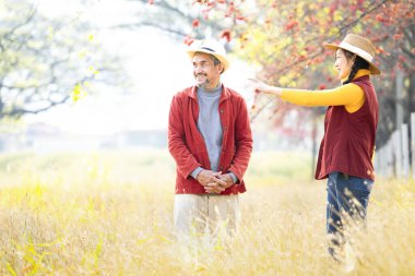 Baba ve kızı, tarım ürünlerini incelemek için çimlerin üzerinde altın güneş ışığıyla tarım arazisinin ortasında duruyorlar. Sonbahar mevsiminde çiftçi aile hayatı kavramı. 