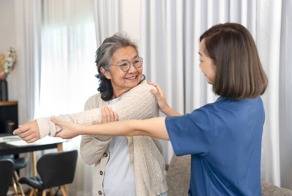 asian senior woman doing physiotherapy that support from a young female nurse,asian older adult having rehab arm stretching at home,concept of elderly lifestyle,home care,home health care